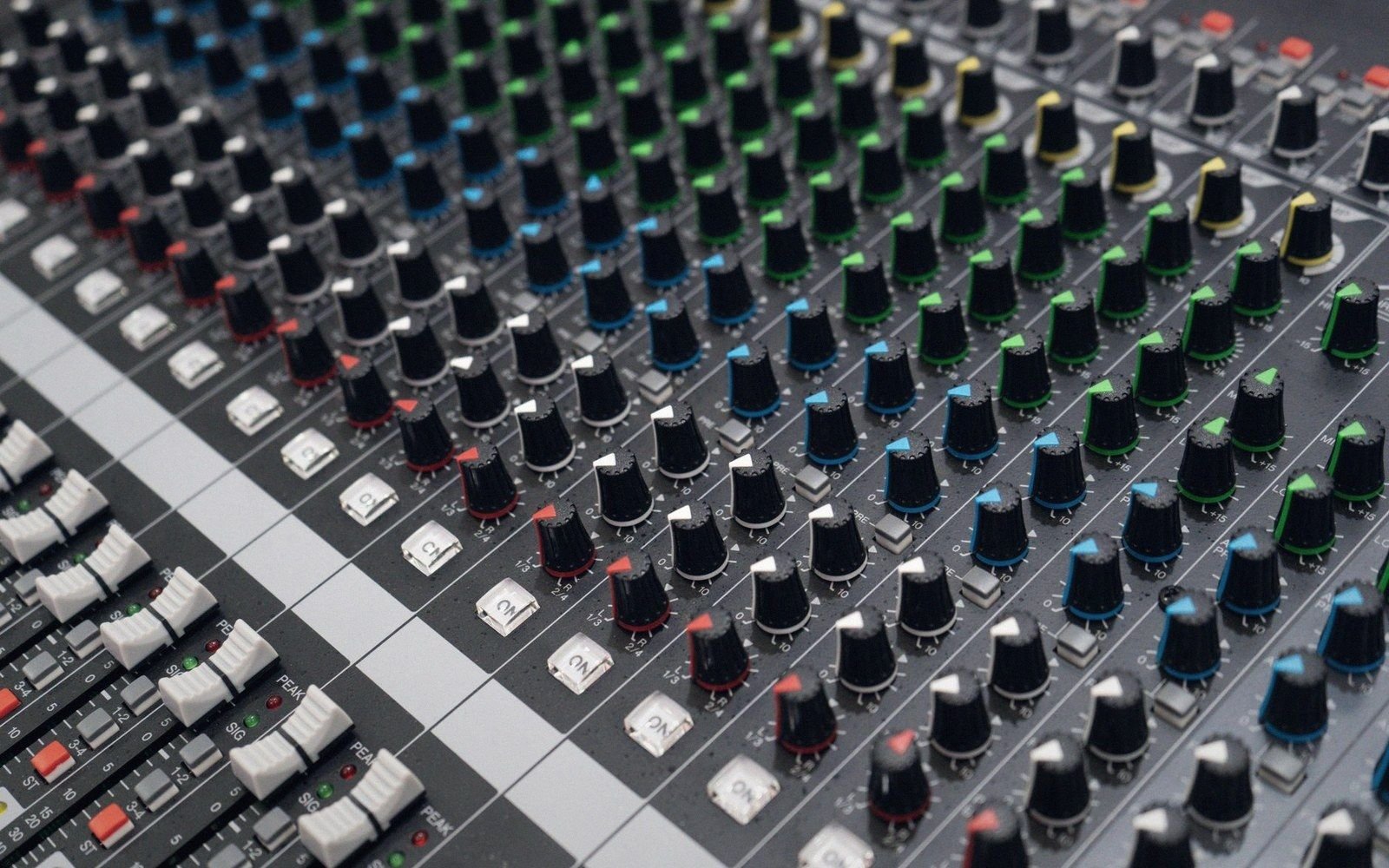 Rows of colour-coded knobs and switches on an audio mixing console