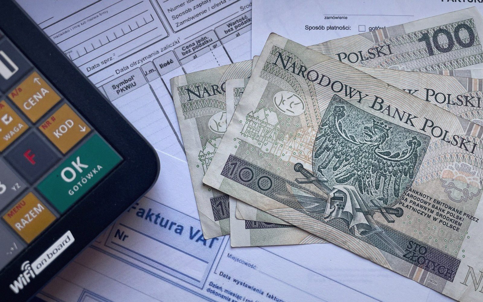 Polish zloty banknotes lying on a VAT invoice next to a cash register keypad