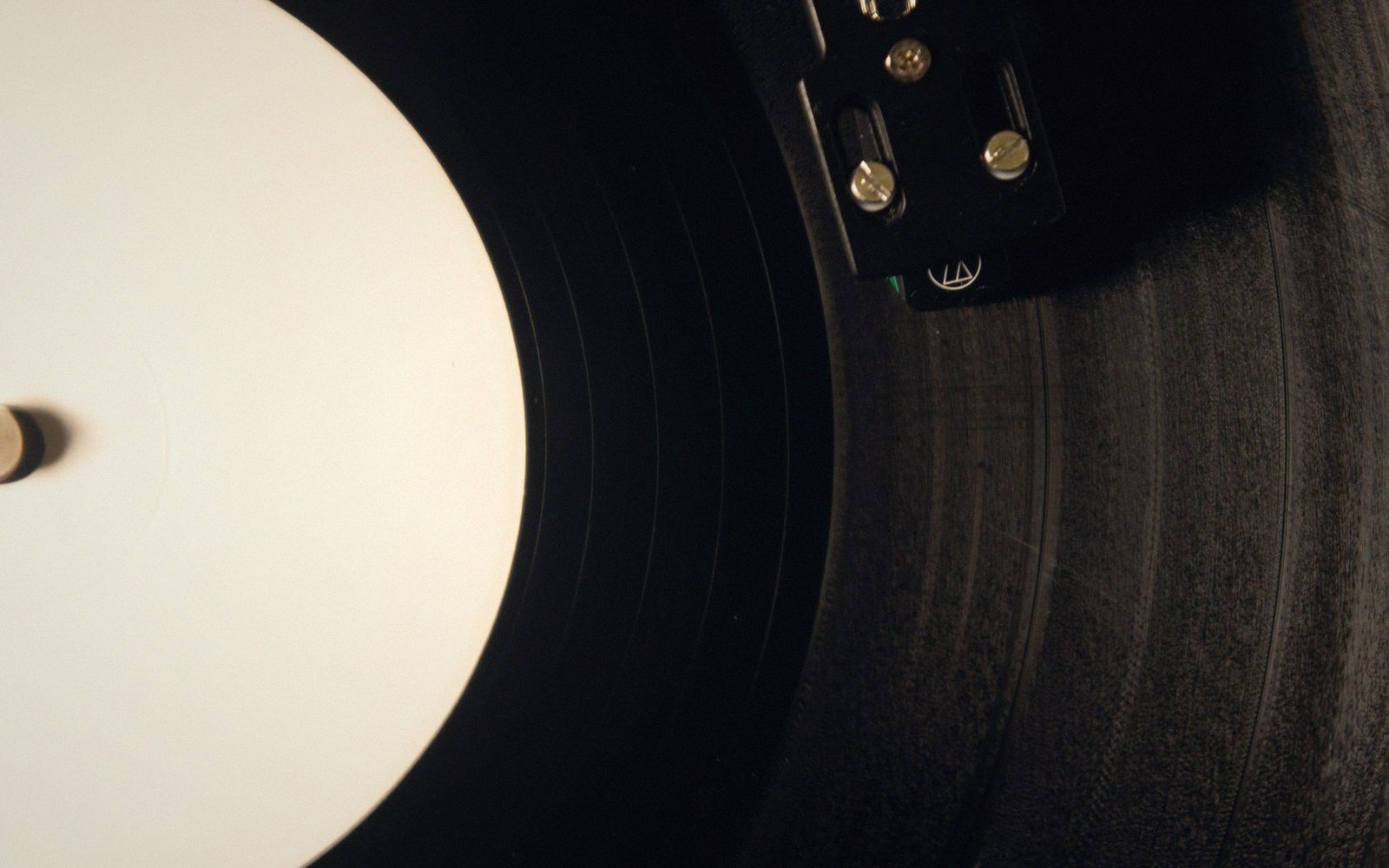 Turntable stylus and cartridge resting on the grooves of a spinning vinyl record