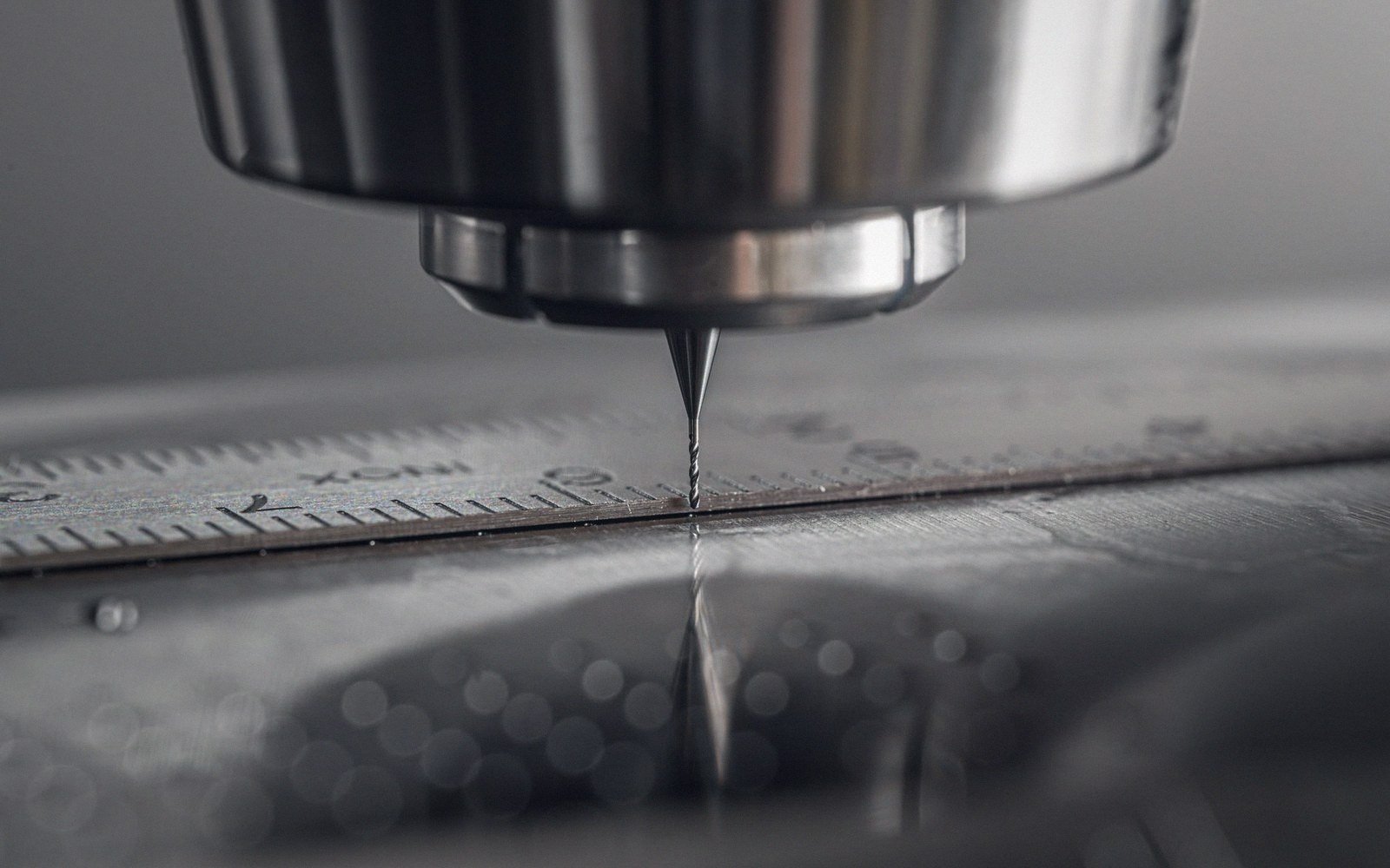 Close-up of a cutting stylus positioned above a metal ruler on a lathe