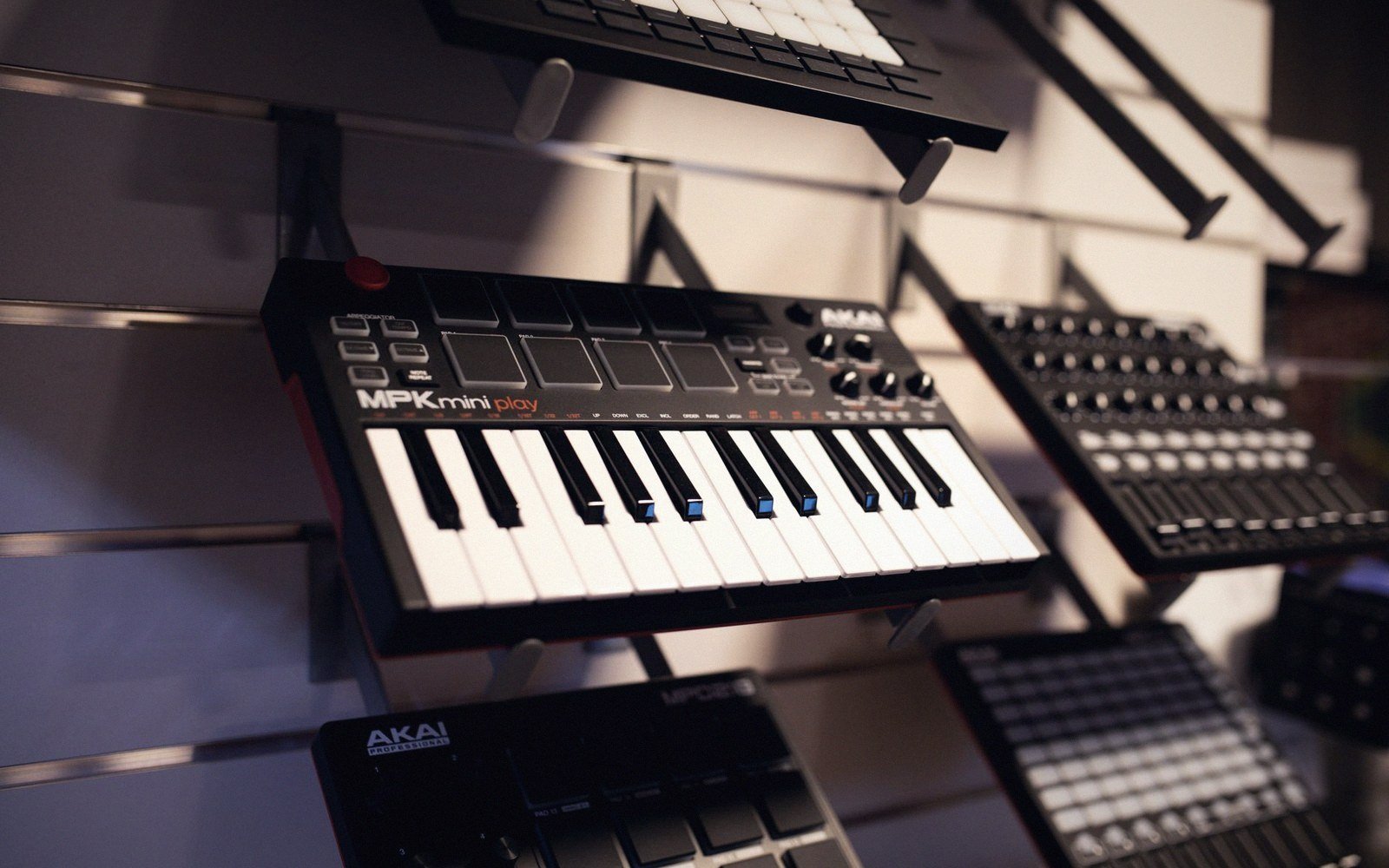 Akai MPK Mini Play keyboard mounted on a display wall with other MIDI controllers