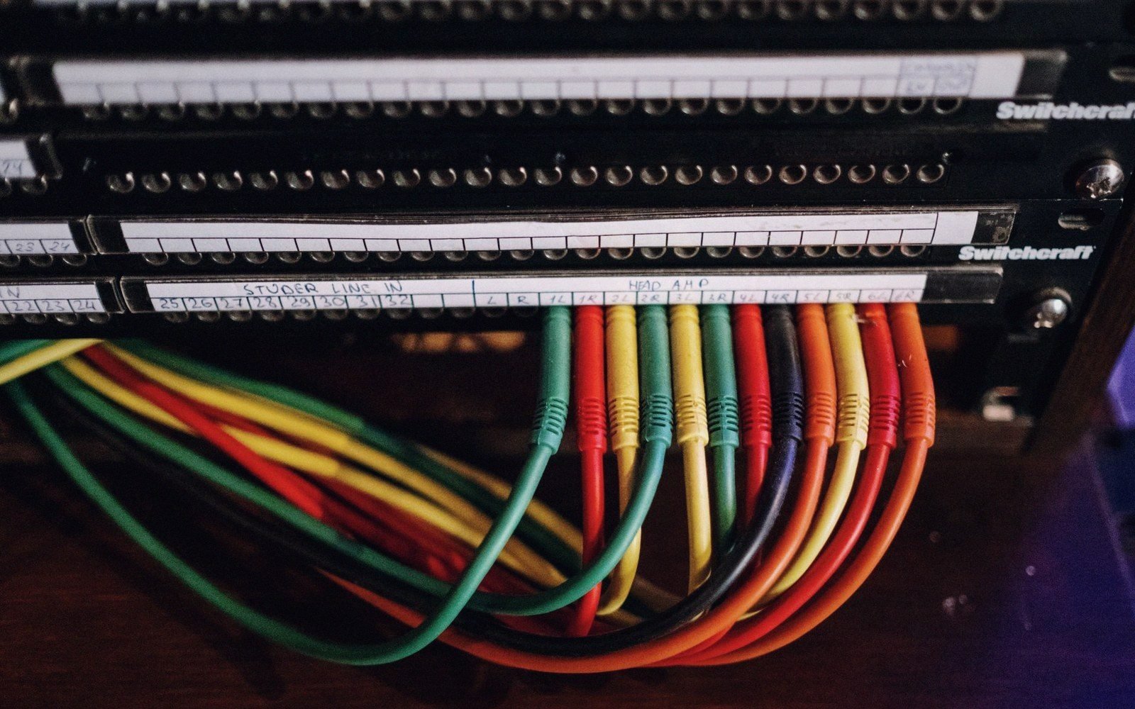 Colorful patch cables plugged into a labeled Switchcraft audio patchbay