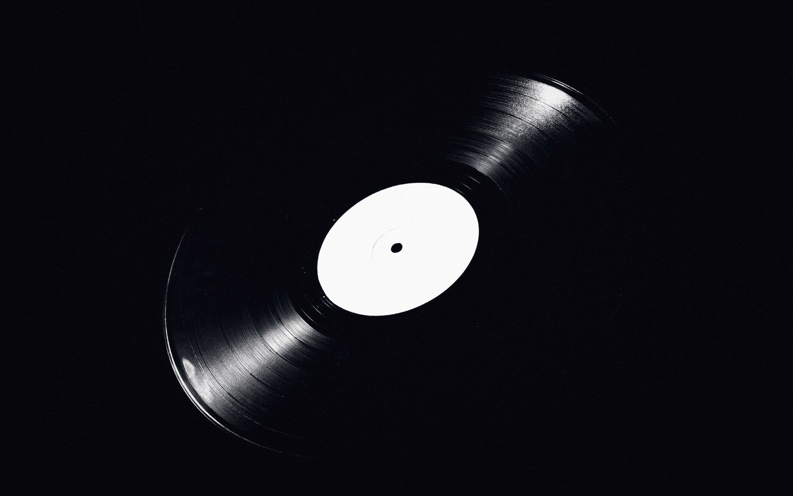 A vinyl record with a blank white label floats against a black background